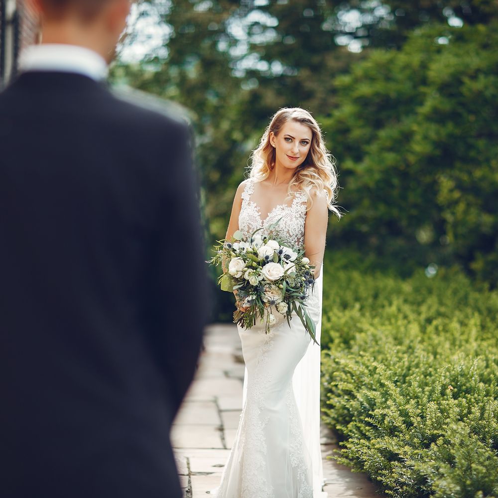 Bride holding her bouquet during a private first look with the groom in a garden