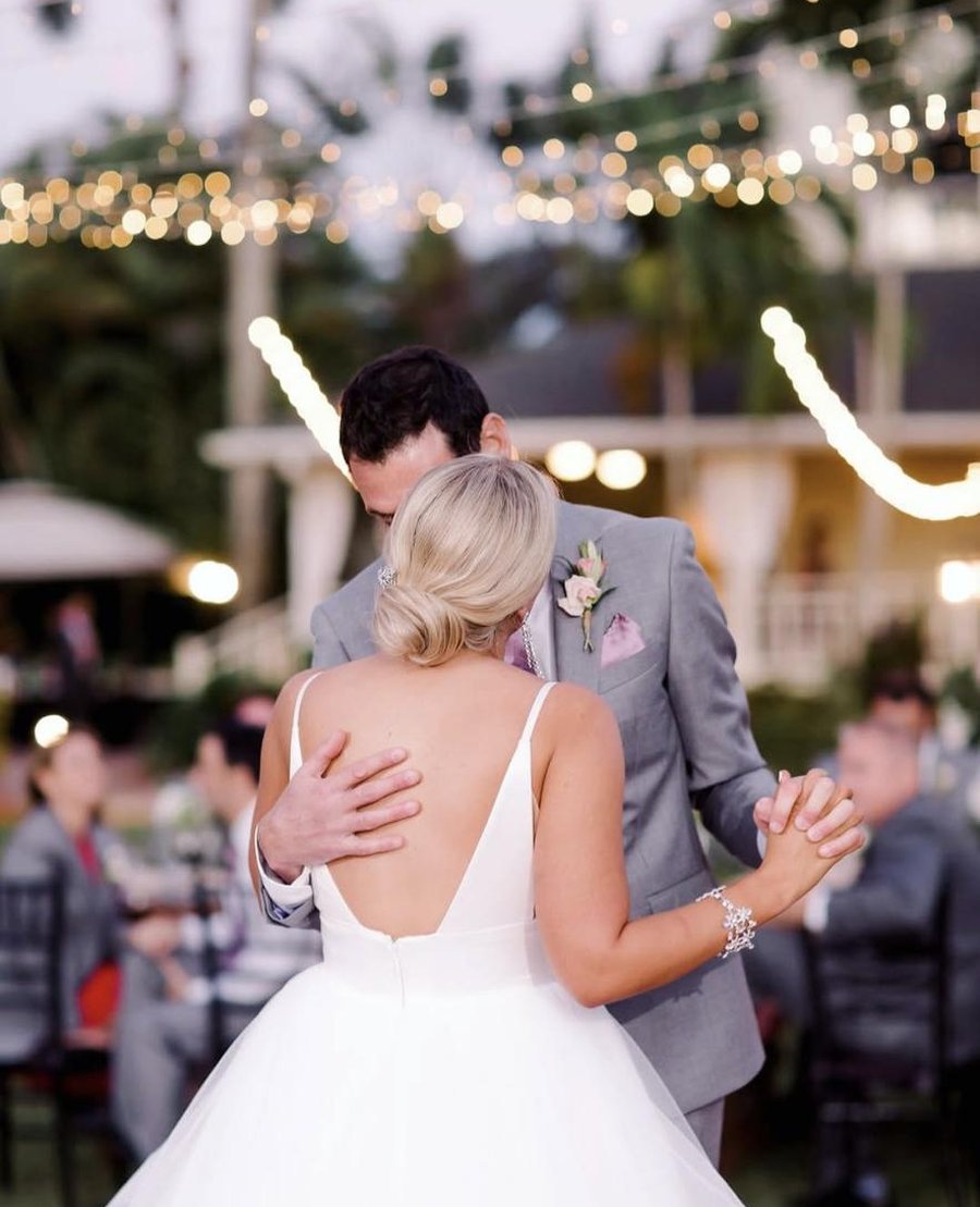 Bride and groom sharing their first dance under string lights