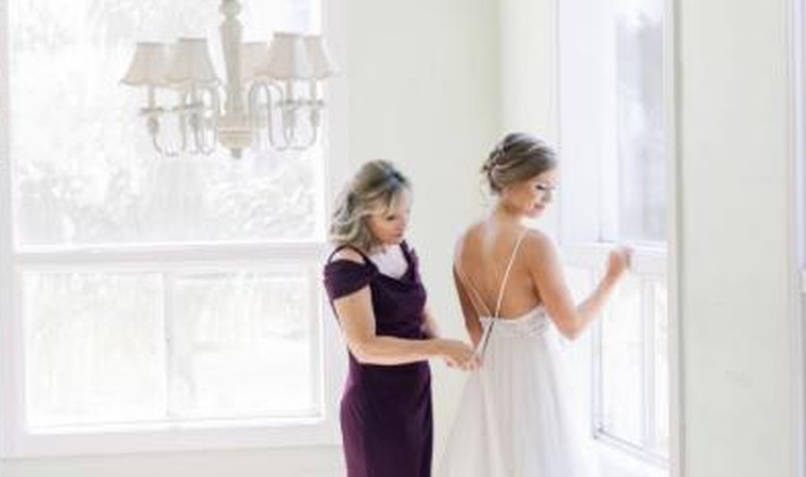 Mother helping bride into her wedding dress